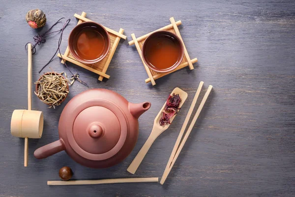 Several types of green tea, black tea, hibiscus tea and tea ceremony attributes - a ceramic teapot, cups, a strainer, chopsticks and tweezers are placed on an old wooden table. Top view Copy space