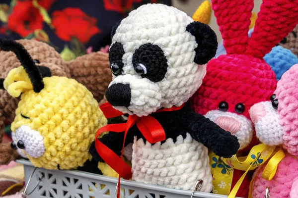 Colorful knitted handmade toys are on display for sale at a souvenir shop on the market. Close-up