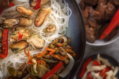 Deniz ürünleri, salata, kırmızı biber ve bir porselen tabak içinde kızarmış yağlı mantar ile pirinç şehriye. Yakın çekim. Üstten görünüm