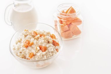 Kabak ve fındık bir cam levha, bir şişe süt ve beyaz bir arka plan üzerinde bir kavanoza dilimlenmiş havuç yulaf ezmesi. Yakın çekim