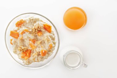 Kabak ve fındık, bir bardak taze meyve suyu ve süt beyaz zemin üzerinde bir sürahi yulaf ezmesi. Üstten görünüm. Kopya alanı.