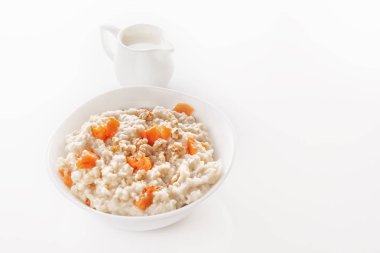 Kabak ve fındık bir tabak ve bir sürahi beyaz zemin üzerine sütlü yulaf ezmesi. Yakın çekim. Kopya alanı