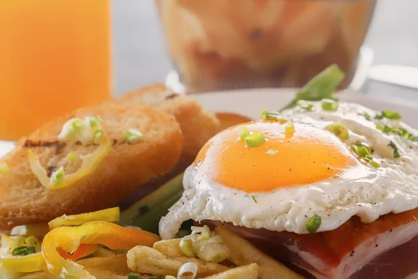 Bir tabak kızarmış adet ekmek, yeşil ve gri bir ahşap masa üzerinde Fransız kızartması ile pastırmalı kızarmış yumurta. Yakın çekim