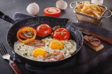 Patates kızartması gri bir tablo ile kızarmış yumurta pastırma ve dökme demir eski bir domates ile pan. Yakın çekim