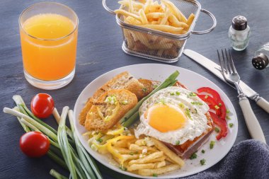 Sahanda yumurta beyaz bir tabak kızarmış adet ekmek, yeşillik, domates, patates kızartması ve bir bardak taze meyve suyu üzerinde gri bir ahşap masa ile pastırmalı. Yakın çekim