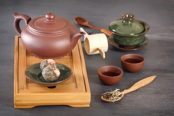 Green tea buds, ceramic teapot, cups, wooden tea tray and other attributes for a traditional tea ceremony