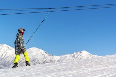 Snowboard ekipman Asansör karşı mavi bir gökyüzü ve dağ zirveleri Kayak bir yokuş yukarı yükselir.