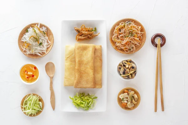Традиционные закуски китайской кухни Dim Sum - тортильи - бинги в тарелке на белом фоне, пряные салаты, овощи, лапша. Вид сверху . — стоковое фото