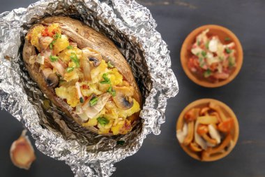 Fırında patates folyo ile pastırma, soğan ve mantar ile çatal gri bir ahşap masa karşı. Yukarıdan görüntüleyin. Yakın çekim