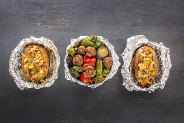 Pişmiş sebze folyo - domates, patlıcan, biber ve fırında patates pastırma, soğan üzerinde gri bir ahşap masa. Üstten Görünüm