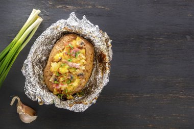 Fırında patates folyo ile pastırma, soğan ve mantar gri bir ahşap masa üzerinde. Uzay kopyalayın. Üstten Görünüm