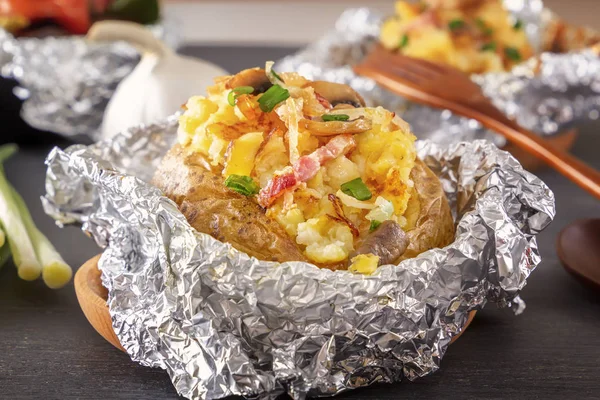 Fırında patates folyo ile pastırma, soğan ve mantar gri bir ahşap masa üzerinde. Yakın çekim