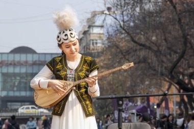 Ulusal kazak kostüm güzel kız halk müzik aleti dombra Nauryz tatil kutluyor sokak sahnesinde oynar.