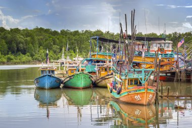 Bulutlarla mavi gökyüzüne karşı Güneydoğu Asya 'da nehirde bir dere içinde renkli balıkçı tekneleri stand