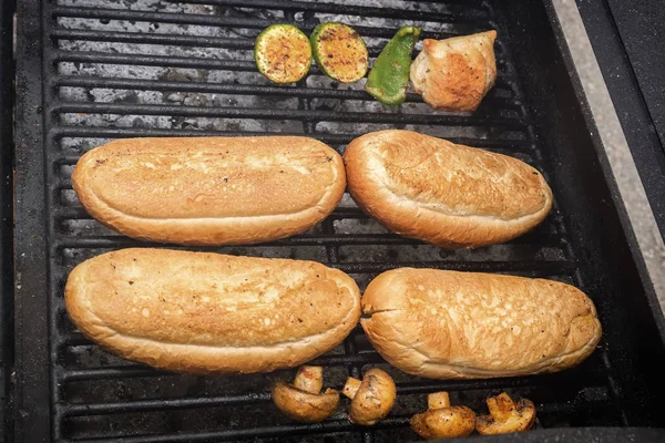 Os pães de cachorro quente aquecem-se em uma grelha em brasas. Comida de rua. Close-up — Fotografia de Stock