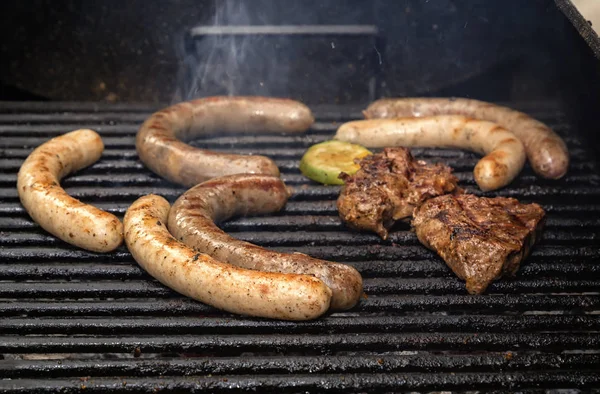 Enchidos e bife de carne são grelhados sobre carvão vegetal. Comida de rua — Fotografia de Stock