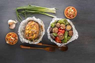 Fırında patates ile pastırma, soğan ve pişmiş sebze folyo - domates, patlıcan, biber üzerinde gri bir ahşap masa. Üstten Görünüm