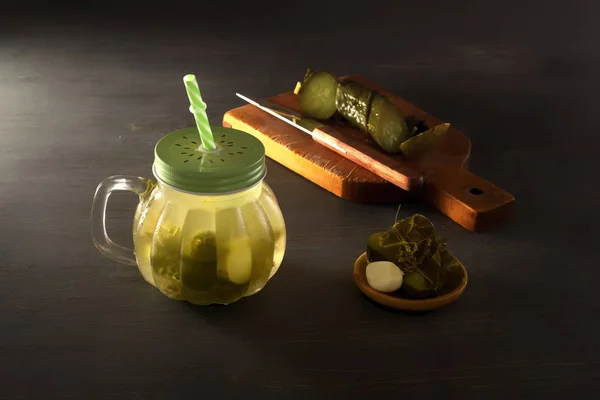 Pepino en vinagre en un frasco sudoroso con una tapa y un tubo en una mesa de madera gris — Foto de Stock