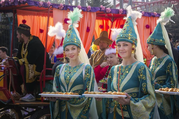 Αλμάτι, Καζακστάν-21 Μαρτίου, 2019. Όμορφα κορίτσια στα εθνικά ρούχα του Καζακστάν κρατούν δίσκους με ένα παραδοσιακό πιάτο-baurσακς κατά τη διάρκεια ενός κοστουμιού εορταστική παρέλαση — Φωτογραφία Αρχείου