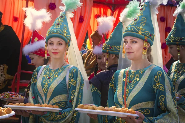 Almat, Kazakistan - 21 Mart 2019.Ulusal Kazak kıyafetleri içinde güzel kızlar geleneksel bir yemek ile tepsiler tutuyor - bir kostüm festival alayı sırasında baursaks. Close