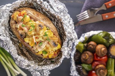 Fırında patates folyo ile pastırma, soğan ve mantar ile çatal üzerinde gri bir ahşap masa. Yakın çekim. Üstten Görünüm