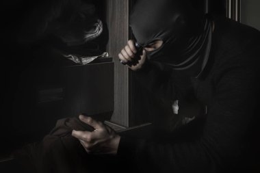 Bir el feneri ile odada bir maske hırsız para ve değerli eşya arıyor