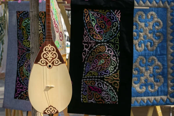 Geleneksel el yapımı halıların arka planında Ulusal Kazak telli müzik aleti dobmra
