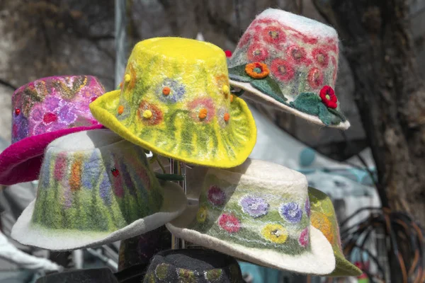 Sombreros de mujer multicolores hechos a mano hechos de fieltro con decoraciones y bordados se venden en la tienda en la calle — Foto de Stock