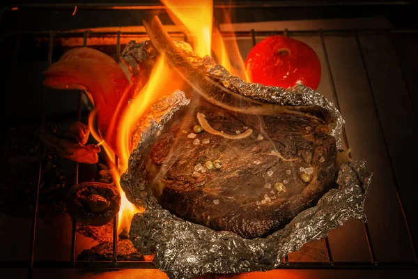 La bistecca di carne in lamina di metallo e verdure è cotta in fuoco. Primo piano — Foto Stock