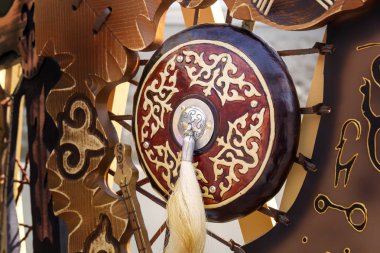 Traditional shield of an ancient Asian warrior with a horsehair brush against the background of national symbols. Close-up clipart