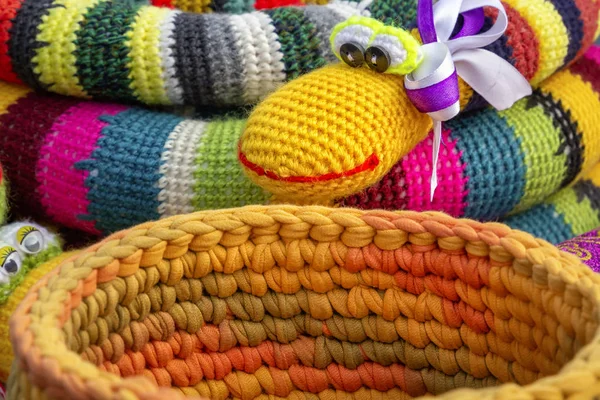 Colorful crocheted handmade toys snake and basket for sale in a souvenir shop on the market. Close-up