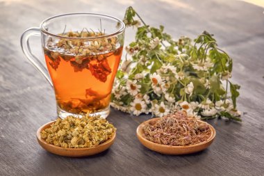 Gri ahşap masada ilaç papatya ve kuru krizantem ile bitkisel çay