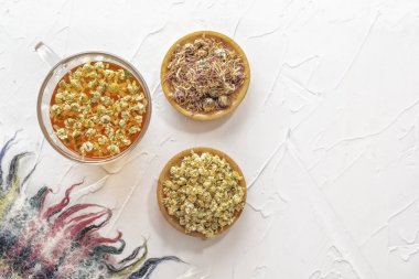 Beyaz bir masada ilaç papatya ve kuru krizantem ile bitkisel çay.