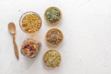 İlaç papatya ile bitkisel çay, kuru krizantem, beyaz bir masada kuru gül yaprakları ve avcılar bir kavanoz