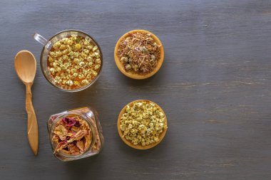İlaç papatya ile bitkisel çay, kuru krizantem, kuru gül yaprakları ve avcılar gri bir masada bir kavanoz. Yukarıdan görüntüleyin. Kopyalama alanı.