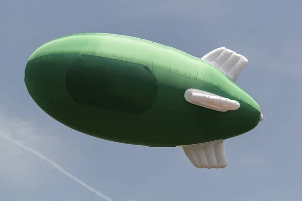 Πράσινο φουσκωτό αερόπλοιο με θέση για το λογότυπο στο φόντο του γαλάζιου ουρανού με σύννεφα. Mockup — Φωτογραφία Αρχείου