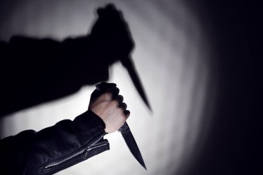 Bir bıçak gölgesi ile duvarın arka planda bir bıçak ile el. Kopyalama alanı