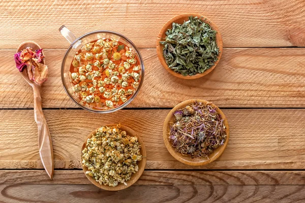 Трав'яний чай з фармацевтичною ромашкою, сухою хризантемою та мисливцями на дерев'яному столі. Вид зверху . — стокове фото
