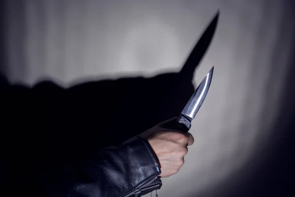 Bir bıçak gölgesi ile duvarın arka planda bir bıçak ile el. Kopyalama alanı