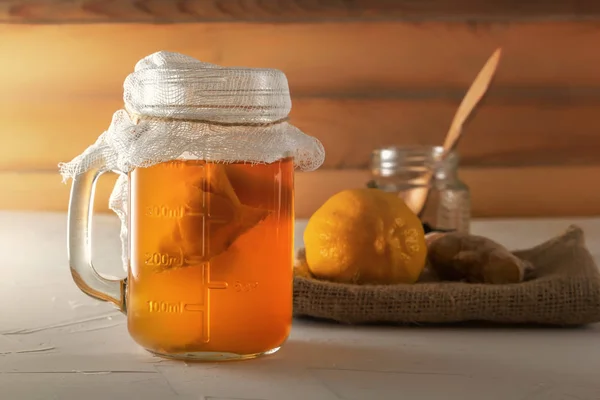 Bebida fermentada casera Kombucha en tarro de cristal con limón y jengibre sobre una mesa de madera. Primer plano —  Fotos de Stock