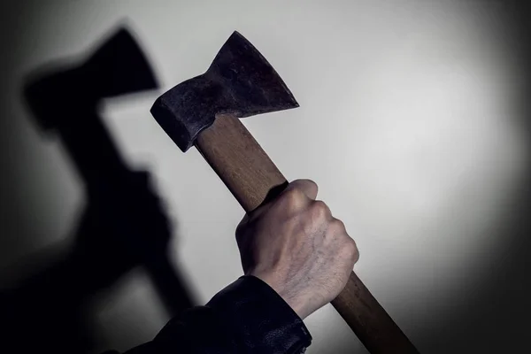 Baltadan gölgesi olan bir duvarın arka planında baltalı bir el. Kopyalama alanı