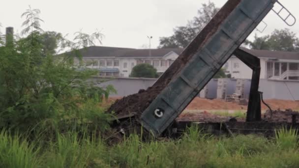 倾卸卡车在大雨中卸载场地的土壤 — 图库视频影像