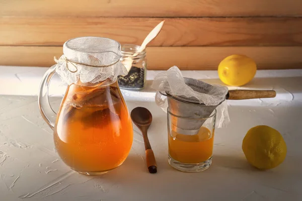 Bebida fermentada casera Kombucha en frascos de vidrio con limón y jengibre sobre una mesa de madera . — Foto de Stock