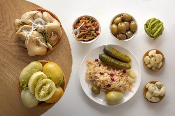 Las setas saladas y los tomates en los platos de madera sobre el fondo de los productos fermentados sobre la mesa blanca. Primer plano. Vista superior — Foto de Stock
