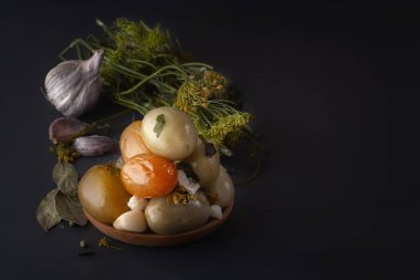 Tuzlu domates tuzlama için baharat ile birlikte koyu bir masada ahşap bir tabakta. Kopya alanı. Düşük anahtar.