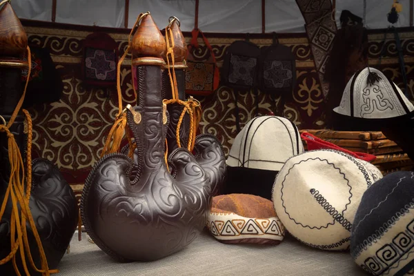 Tradicional frasco de cuero kazajo para bebidas de madera sobre el telón de fondo de sombreros de fieltro en una yurta - el hogar de los nómadas. Primer plano —  Fotos de Stock