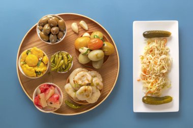 Fermente ürünler lahana, biber, turşu, domates, mantar, kabak, sarımsak mavi bir masada. Üstte görüntü