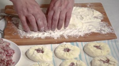 Kadın eli, mutfak masasında ev yapımı turtalar için hamur hamuruyla bir bıçağı porsiyonlu parçalara ayırdı.