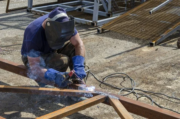 Bir işçi bir metal depoda bir metal yapı kaynak.