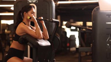 Çekirdek ve kol kaslarını çalıştıran formda bir kadın enerji dolu bir alanda spor aletleri kullanıyor..